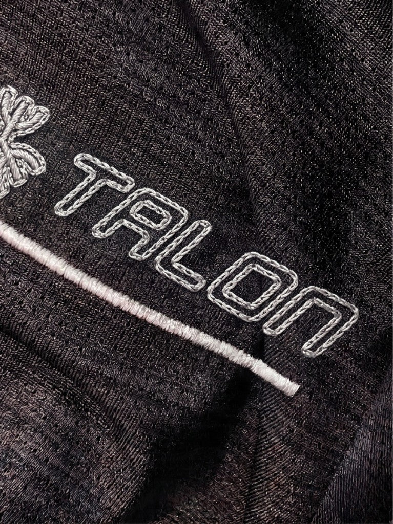 TALON chain stitch embroidery close-up on black technical mesh sportswear fabric.