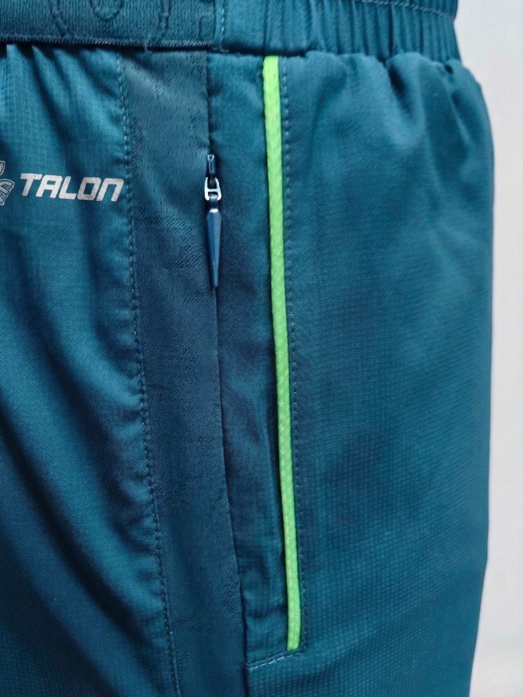 TALON concealed hidden zipper pocket on teal technical sportswear with lime accent trim.