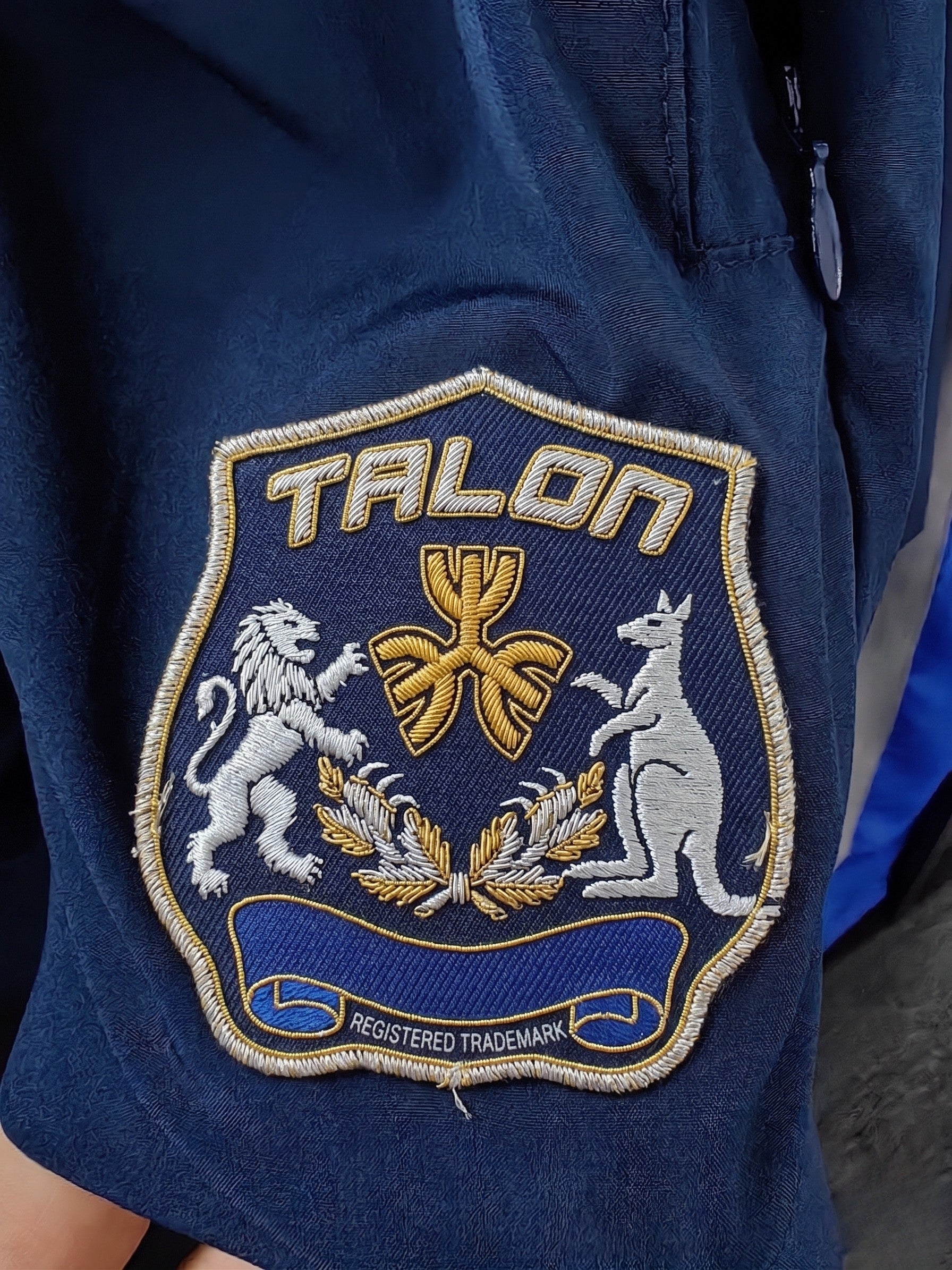 TALON shield-shaped embroidered logo patch badge on navy sportswear fabric.