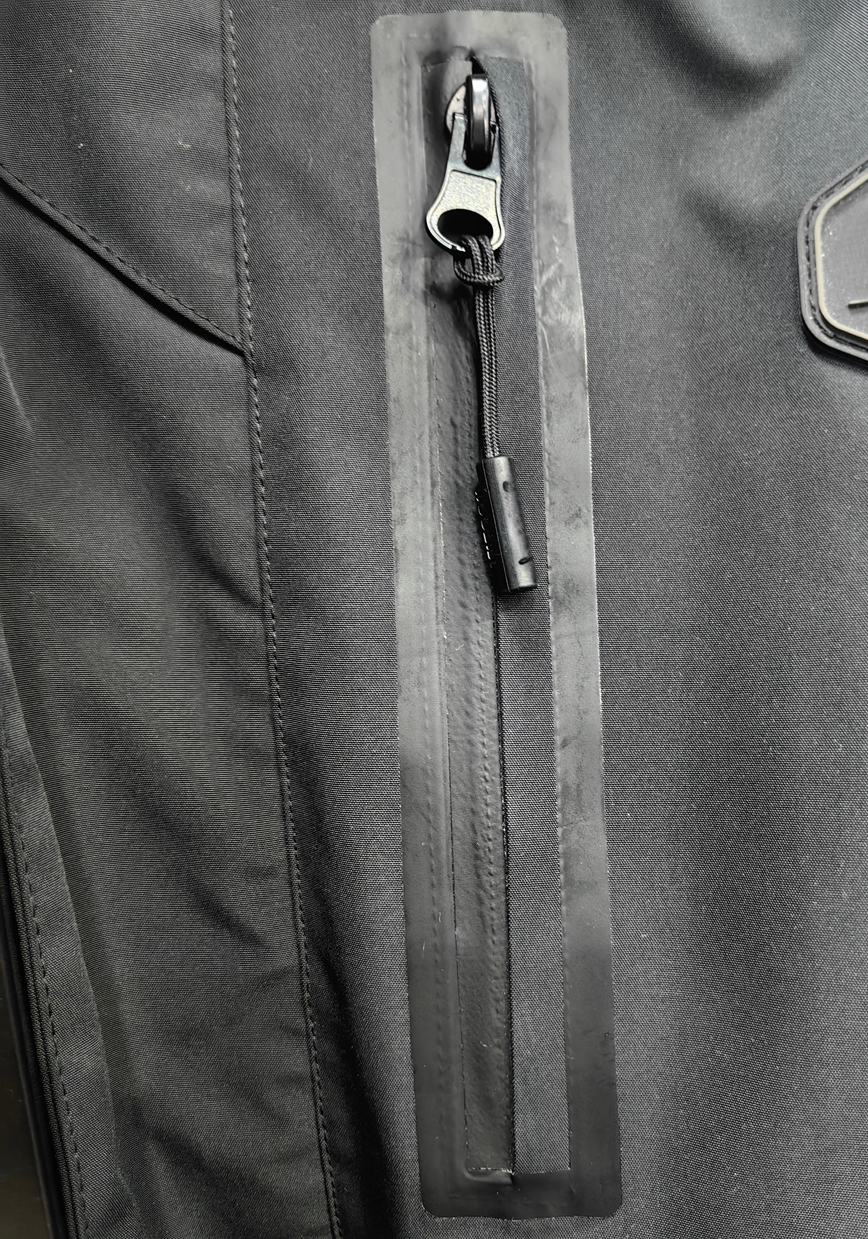 TALON raised silicone branding detail on black technical mesh sportswear fabric.